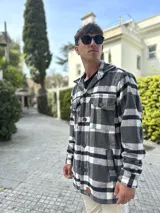 Sobrecamisa gris y blanca a cuadros con cuello camisero, cierre con botones y bolsillos con solapa en el pecho.