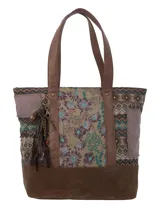 Cartera tipo tote con diseño patchwork que combina paneles de tela estampada con motivos florales y geométricos, con detalles en cuero sintético marrón y base de gamuza. Incluye correas de hombro fijas y un colgante decorativo con borlas y cuentas metálicas.