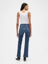 Jean de corte bootcut y tiro bajo, en color azul oscuro con acabado lavado. Presenta diseño de cinco bolsillos, cierre frontal con botón y cremallera, y costuras reforzadas en el ruedo.