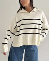 Sweater estilo chomba con cierre frontal, confeccionado en tejido bremer rayado de manga larga. Presenta un diseño amplio y moderno con cuello polo.