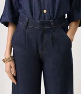 Pantalón de jean azul oscuro de corte recto y tiro alto, inspirado en la sastrería. Presenta pinzas delanteras, bolsillos funcionales y pretina con pasacintos.