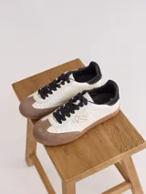 Championes de cuero con diseño bicolor en blanco y marrón, con puntera de gamuza, cordones negros y logo bordado en el lateral.