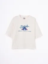 Remera blanca de corte holgado con estampado frontal de Stitch y texto Ohana Varsity Club. Presenta cuello redondo y mangas cortas.