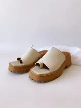 Sandalias de cuero crudo con tira ancha sobre los dedos y suela track color caramelo.