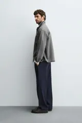 Camisa de denim de algodón, color gris oscuro lavado, de corte holgado (boxy fit). Presenta cuello solapa, manga larga con puño abotonado, bolsillo de plastrón en el pecho y cierre frontal con botones.