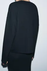 Top de tejido soft con cuello redondo, manga larga y bajo recto.