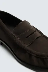 Mocasín de vestir confeccionado en piel con acabado de serraje, presenta un diseño clásico con detalle de antifaz en el empeine y suela a contraste con un ligero tacón.