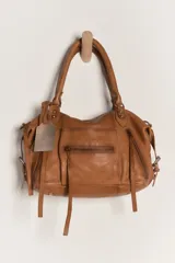 Cartera de cuero color marrón, con efecto lavado de aspecto usado, asas de mano, bolsillos frontales con cierre y tiras colgantes decorativas.