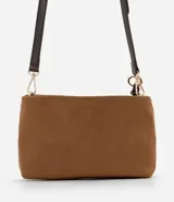 Bolso bandolera de tamaño mediano confeccionado en gamuza sintética color marrón tostado. Presenta un formato rectangular estructurado, cierre superior con cremallera y correa larga ajustable en color marrón oscuro. Incluye un detalle decorativo de tiras anudadas en uno de los laterales.