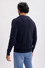Buzo de punto en color azul marino con escote en V y puños acanalados. Diseño clásico y versátil, ideal para combinar con diversas prendas.