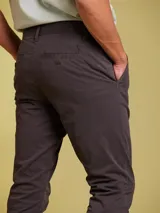 Pantalon tipo chino de corte ajustado, color gris oscuro, con cierre de boton y cremallera, y bolsillos laterales.