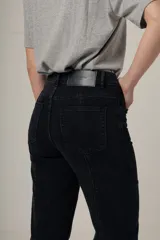 Jean de denim negro, tiro alto y corte recto, con costuras verticales decorativas en el frente.