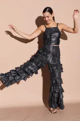 Pantalón negro brillante con volados en capas a lo largo de las piernas, de corte recto y tiro alto.