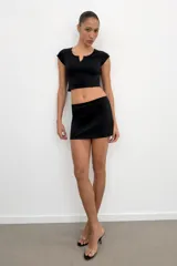 Falda corta gris melange de tiro medio con cintura elástica, confeccionada en hilatura con mezcla de algodón. Cuenta con forro interior tipo shorts del mismo tejido.