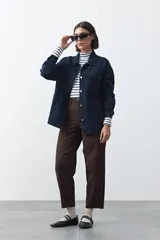 Sobrecamisa de jean color negro con silueta relajada, cuello camisero, cierre frontal con botones metálicos, bolsillos frontales y cinturón ajustable en la cintura.