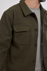 Sobrecamisa de tejido grueso sin forro, con diseño de corte holgado y silueta cuadrada. Presenta cuello clásico, cierre frontal con botones mate y dos bolsillos en el pecho con solapa.