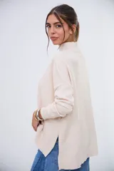 Sweater beige de cuello alto, manga larga y corte holgado con aberturas laterales en el dobladillo.