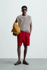 Camiseta sin mangas de punto con cuello redondo, tejido abierto a rayas horizontales negras y blancas, con ribetes en color crema.