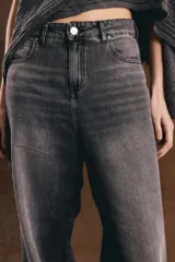 Jean de denim tiro alto con diseño baggy de corte ancho y relajado, color negro con efecto acid wash. Presenta cierre frontal con botón metálico y bolsillos clásicos.