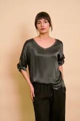Blusa holgada de satén color beige, con escote en V y mangas largas con trabilla para sujetar remangadas.