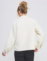 Chaqueta capitoneada de color negro con diseño de rombos, cuello con solapa, cierre frontal con botones metálicos y bolsillos delanteros.