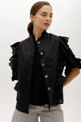 Chaleco negro de lino con cuello mao, cierre frontal con botones y volados en hombros y bolsillos.