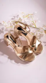 Sandalias de tacón bajo color dorado, con tiras cruzadas en el empeine, pulsera al tobillo con hebilla y plantilla acolchada.