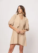 Vestido corto color beige, de corte oversize, con escote en V y mangas globo. Incluye cinturón marrón con hebilla dorada.