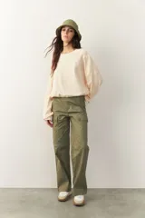 Buzo color crema, cropped, de manga larga con puños y cordones ajustables en la cintura.