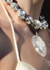 Collar de metal plateado con diseño de cuentas de formas orgánicas y abstractas, con cadena de ajuste y cierre de mosquetón.