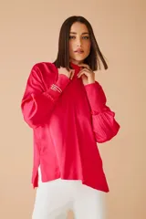 Blusa fucsia de satén con cuello alto fruncido y mangas largas abullonadas con puños elásticos.