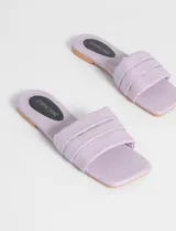 Sandalias bajas color lila, con tira ancha acolchada y suela plana.