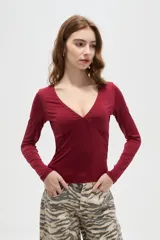 Remera de manga larga color bordó, con escote en V profundo y corte ajustado al cuerpo.