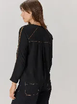 Remera negra de manga larga con detalles de costuras y franjas en contraste de color tostado en las mangas y la espalda.