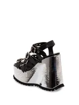 Sandalias negras de cuero con plataforma plateada y tiras con hebillas.