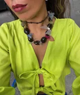 Blusa color verde lima con escote en V, mangas largas abullonadas con puños elásticos y cierre frontal con lazos.