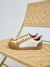 Championes de cuero con diseño de paneles en tonos crema, mostaza y detalles metalizados en el talón. Presentan cordones planos y logo bordado en el lateral.