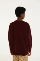 Sweater de punto oversized bordó con cuello redondo y mangas largas con terminaciones acanaladas. Presenta un estampado frontal de estilo tropical con el texto 'Farm Rio' y 'Latino America', acompañado de ilustraciones de una palmera, un tucán y frutas.