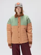 Campera acolchada de diseño colorblock, con el pecho y hombros en tono bordó y el cuerpo y mangas en color beige. Presenta cuello camisero y puños de pana negra, cierre frontal oculto con botones a presión y costuras pespuntadas en patrón cuadriculado.