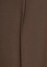 Pantalón de vestir marrón de tiro bajo y diseño wide leg, con pinzas frontales, trabillas para cinturón, bolsillos laterales y cierre oculto con botón, gancho y cremallera.