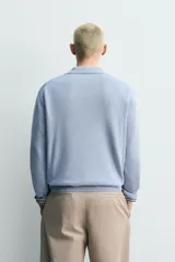 Polo de punto regular fit color celeste, tejido con mezcla de cáñamo y algodón. Presenta cuello tipo solapa con abertura frontal y manga larga, con terminaciones en rib.