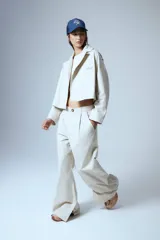 Pantalón de gabardina color crudo, estilo sastrero, de tiro bajo y corte recto. Presenta pinzas delanteras, presillas anchas, tajo interno en la botamanga y badana de PU en la cintura trasera.