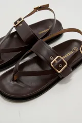 Sandalias negras de eco cuero estilo chunky, con diseño de tiras cruzadas y hebilla metálica dorada en la parte superior. Cuenta con tira ajustable en el talón.