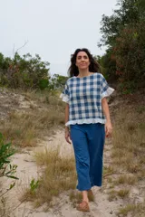 Top de tela a cuadros azul y blanco, con corte cuadrado, mangas cortas con volados y ruedo con volados.