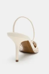 Zapato de tacón destalonado color beige, con cuerpo de tejido perforado, escote en pico, tira elástica trasera, tacón alto fino y acabado en punta.