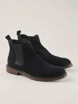Bota Chelsea de gamuza gris con elásticos laterales, suela de goma marrón y tirador trasero.