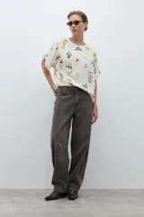 Blusa de manga corta, color crudo, con estampado floral en tonos azules, amarillos y rojos. Presenta cuello redondo y volados en los puños.