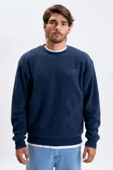 Buzo de polar azul marino con cuello redondo, mangas largas y puños elásticos. Presenta un bordado sutil en el pecho con la frase Jungle Bungle.