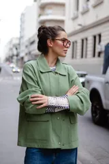 Chaqueta de lana afieltrada en color amarillo mostaza, con cuello camisero, cierre frontal con broches a presión y bolsillos delanteros. Presenta un diseño de espalda con apertura para mayor movimiento.