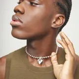 Collar de plata con cadena de bolitas y un dije central con forma de corazón irregular. El cierre tiene un pequeño dije con el logo grabado.